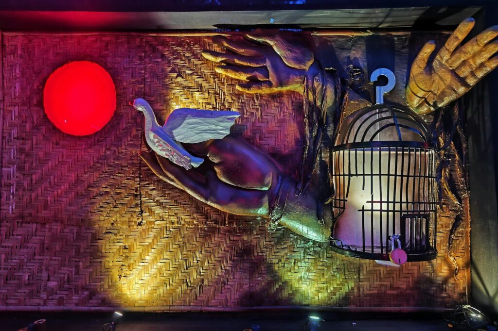 A bird in hands with a cage and red light